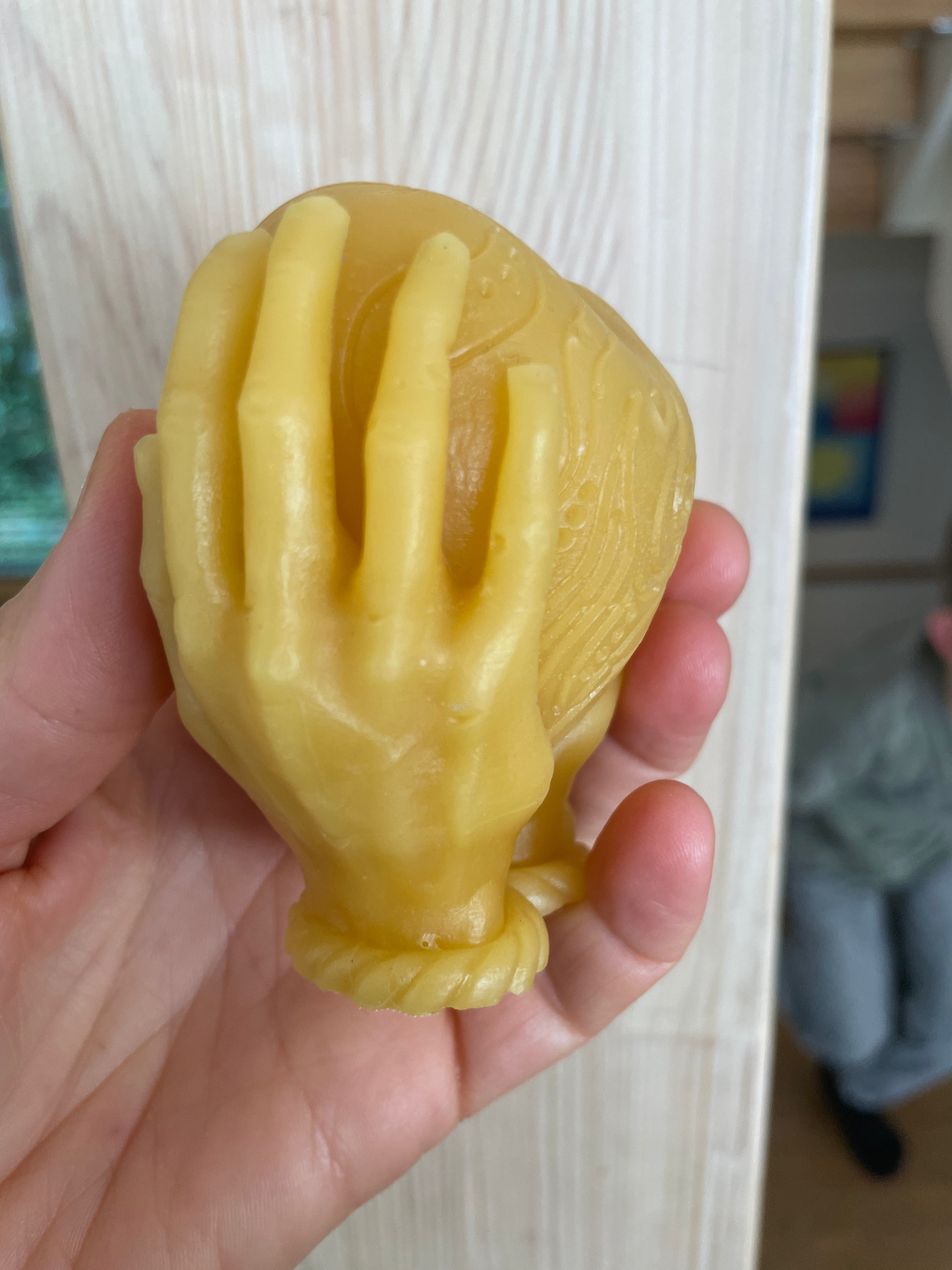 Bienenwachskerze-Herz in Händen