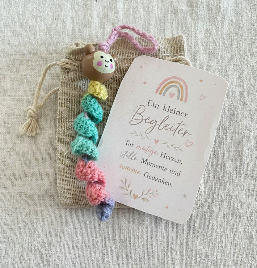 Handgemachtes gehäkeltes Mutmacher Äffchen in Regenbogenfarben mit Karte „Ein kleiner Begleiter“ und Stoffbeutel 🌈