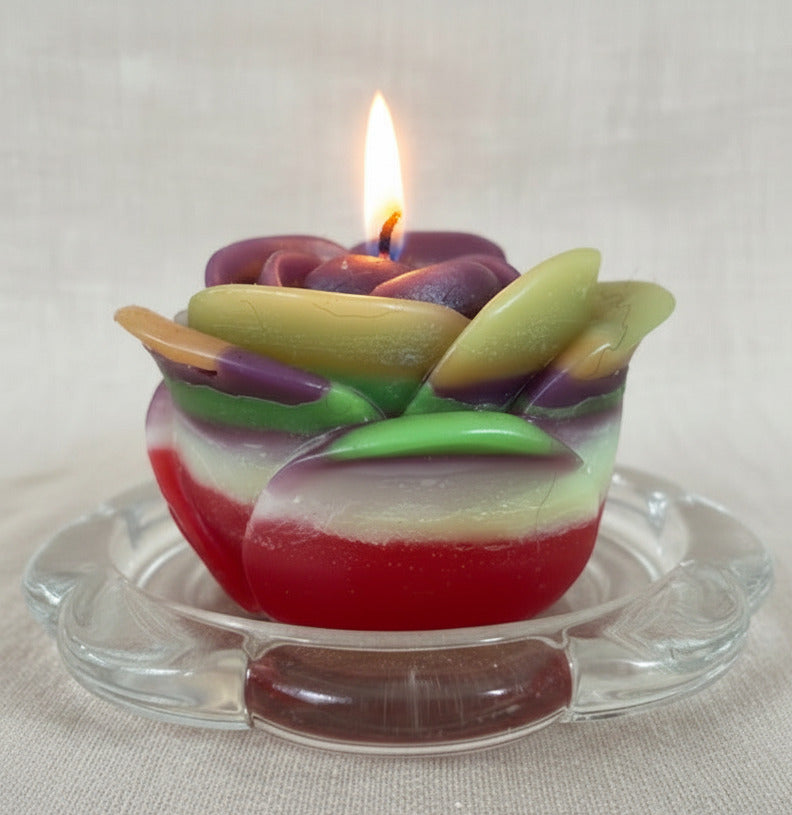 Bunte handgemachte Blumenkerze aus Kerzenresten brennend, nachhaltige Upcycling Deko Kerze im Glasuntersetzer