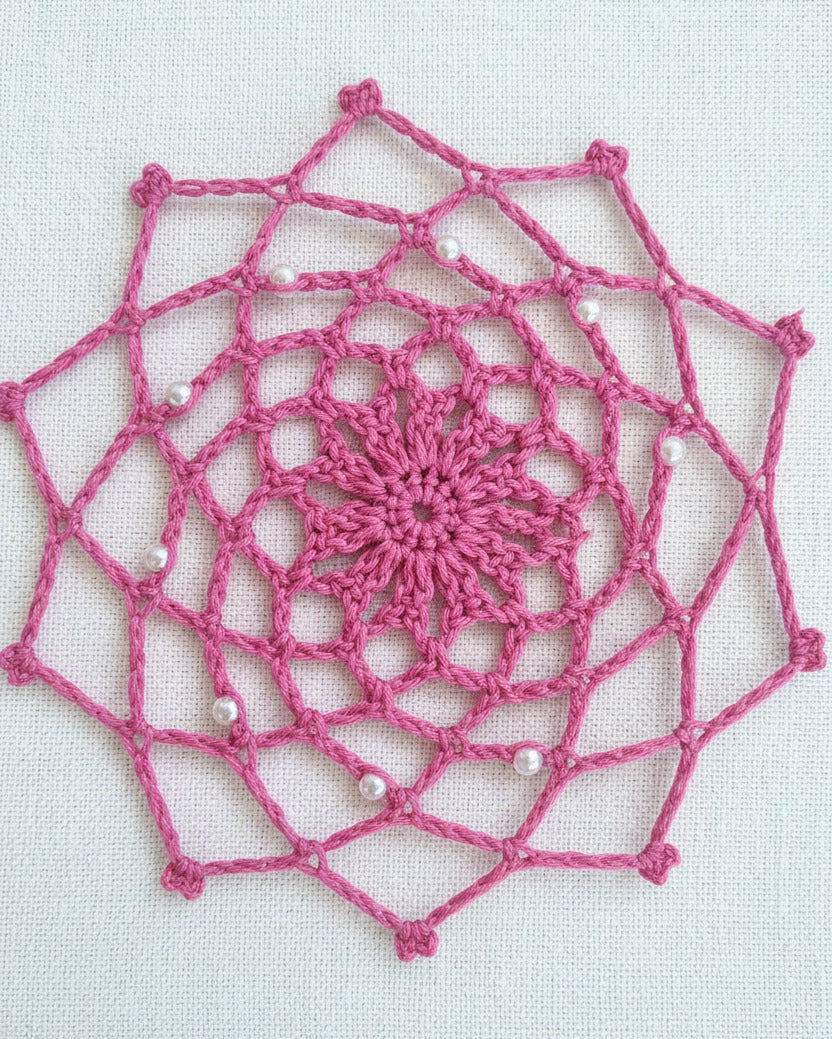 Handgehäkelter rosa Traumfänger mit Perlen im filigranen Mandala-Muster auf hellem Hintergrund