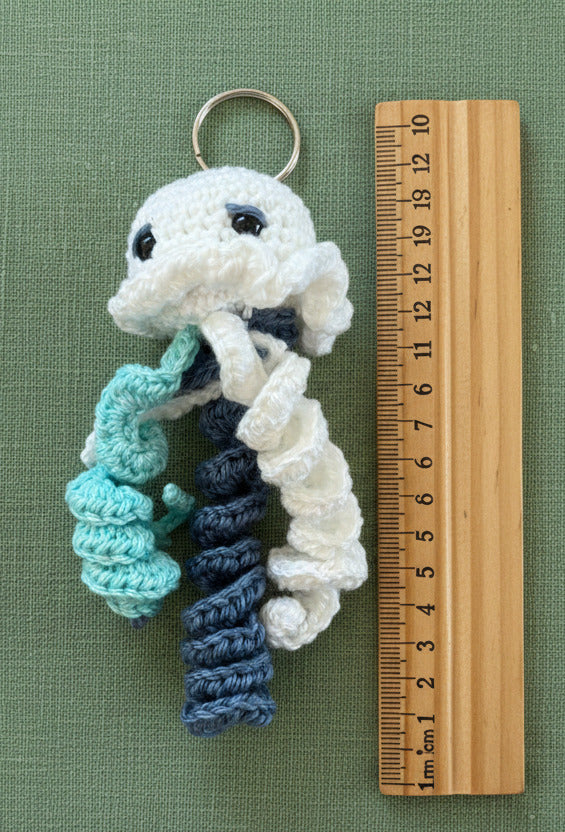 Gehäkelte Qualle Schlüsselanhänger in Weiß und Blau im Größenvergleich mit Lineal, handgemacht im Amigurumi Stil