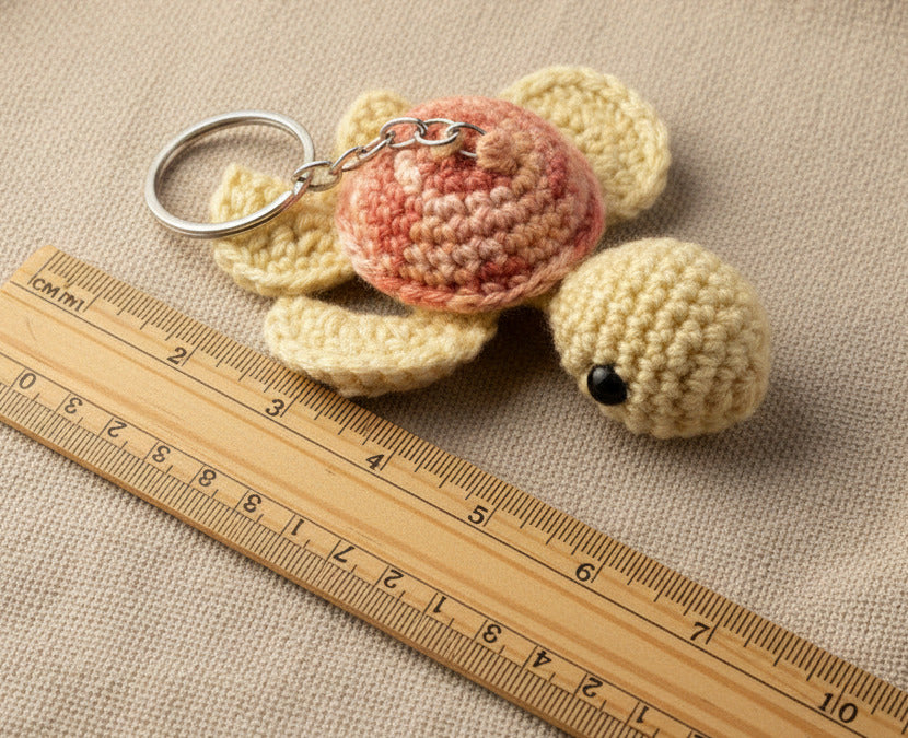 Gehäkelte Schildkröte Schlüsselanhänger in Beige mit Lineal als Größenvergleich, handgemacht im Amigurumi Stil