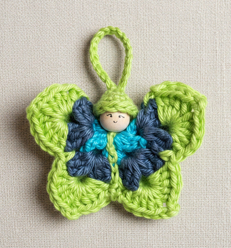 Gehäkelter Schmetterling mit kleiner Figur in Grün und Blau – handgemachter Anhänger