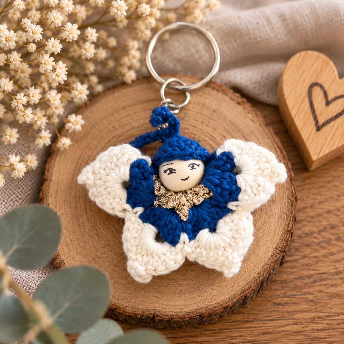 Kleiner handgemachter gehäkelter Schmetterling in Blau und Weiß mit Schlüsselring, dekoriert auf einer Holzscheibe.