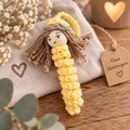 Handgemachter gehäkelter Schutzengel in Gelb mit braunen Haaren und goldenem Heiligenschein, liebevoll als kleiner Glücksbringer dekoriert.