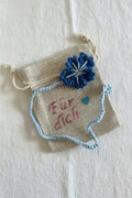 Handgemachtes gehäkeltes Lesezeichen mit blauer Blume auf kleinem Stoffbeutel mit Aufschrift „Für dich“ 💙
