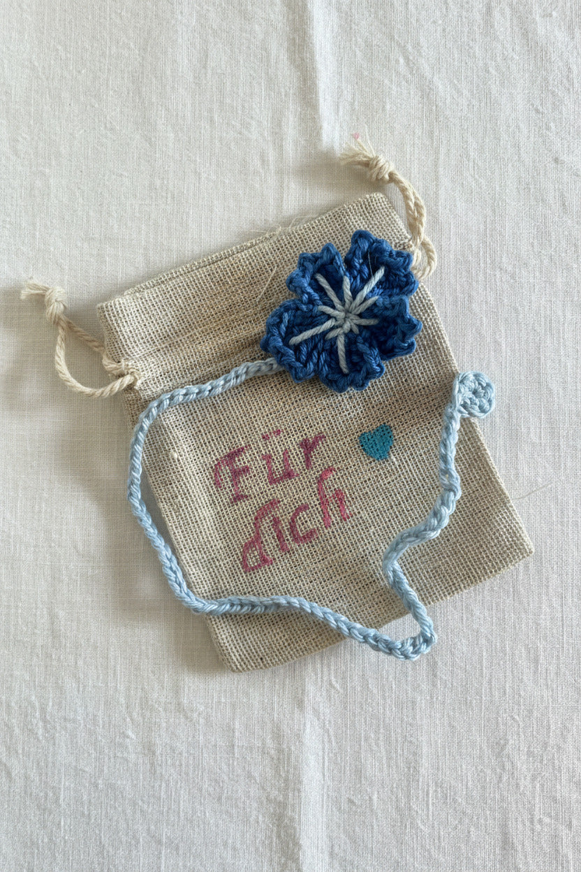 Handgemachtes gehäkeltes Lesezeichen mit blauer Blume auf kleinem Stoffbeutel mit Aufschrift „Für dich“ 💙