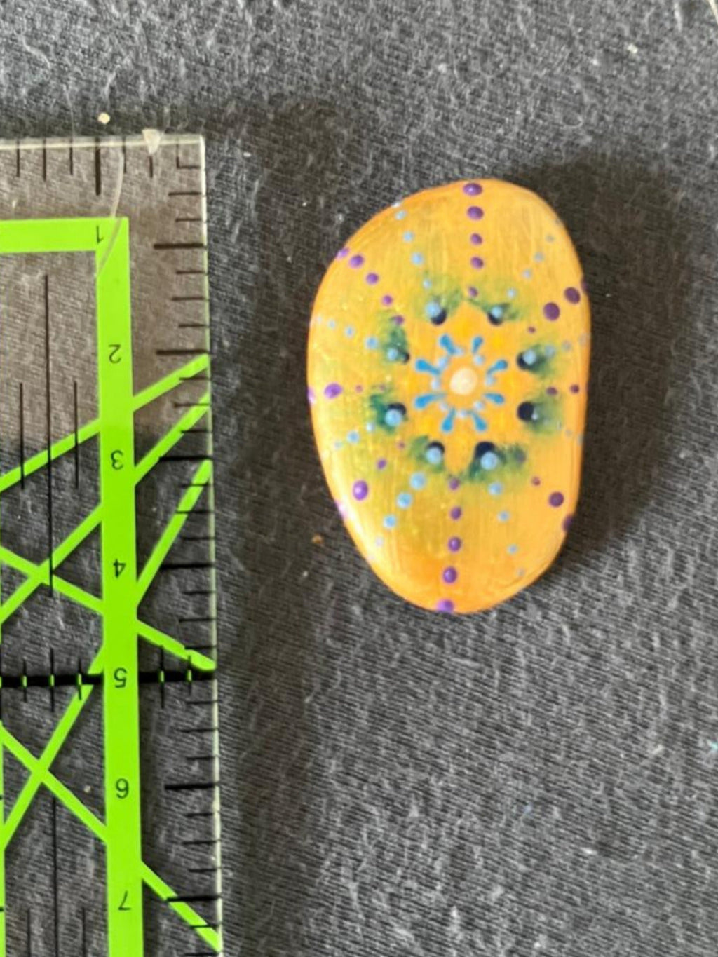 Handbemalter Glücksstein mit Mandala-Blütenmuster in Blau, Grün, Weiß und Violett auf warmgelbem Stein. Liebevoll gestalteter Glücksbringer im Taschenformat