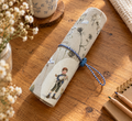 Handgemachtes Rollmäppchen mit Schaf- und Schäfermotiv für Stifte, Pinsel und Häkelnadeln auf Holztisch