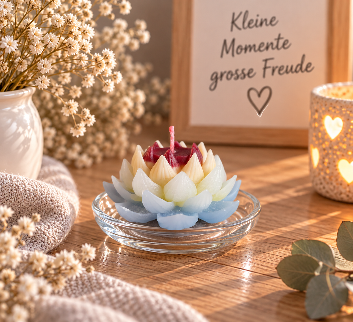 Handgemachte Lotuskerze aus Kerzenresten in Blau, Creme und Rot als stimmungsvolle Dekoration auf einem Glasteller.