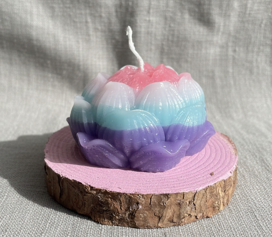 Lotuskerze in Blau und Rosa auf Holzscheibe als dekorative Blütenkerze