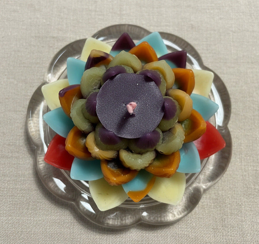 Mehrfarbige Lotusblüten Kerze von oben auf Glasuntersetzer als dekorative Upcycling Kerze
