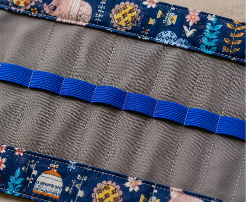 Detailansicht eines handgenähten Rollmäppchens mit blauen Gummischlaufen und gemustertem Stoff