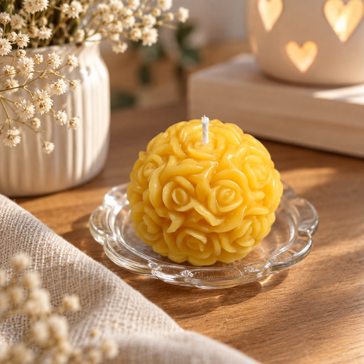 Gelbe handgemachte Rosenkerze auf einem Glasteller in warmer, gemütlicher Wohnatmosphäre.