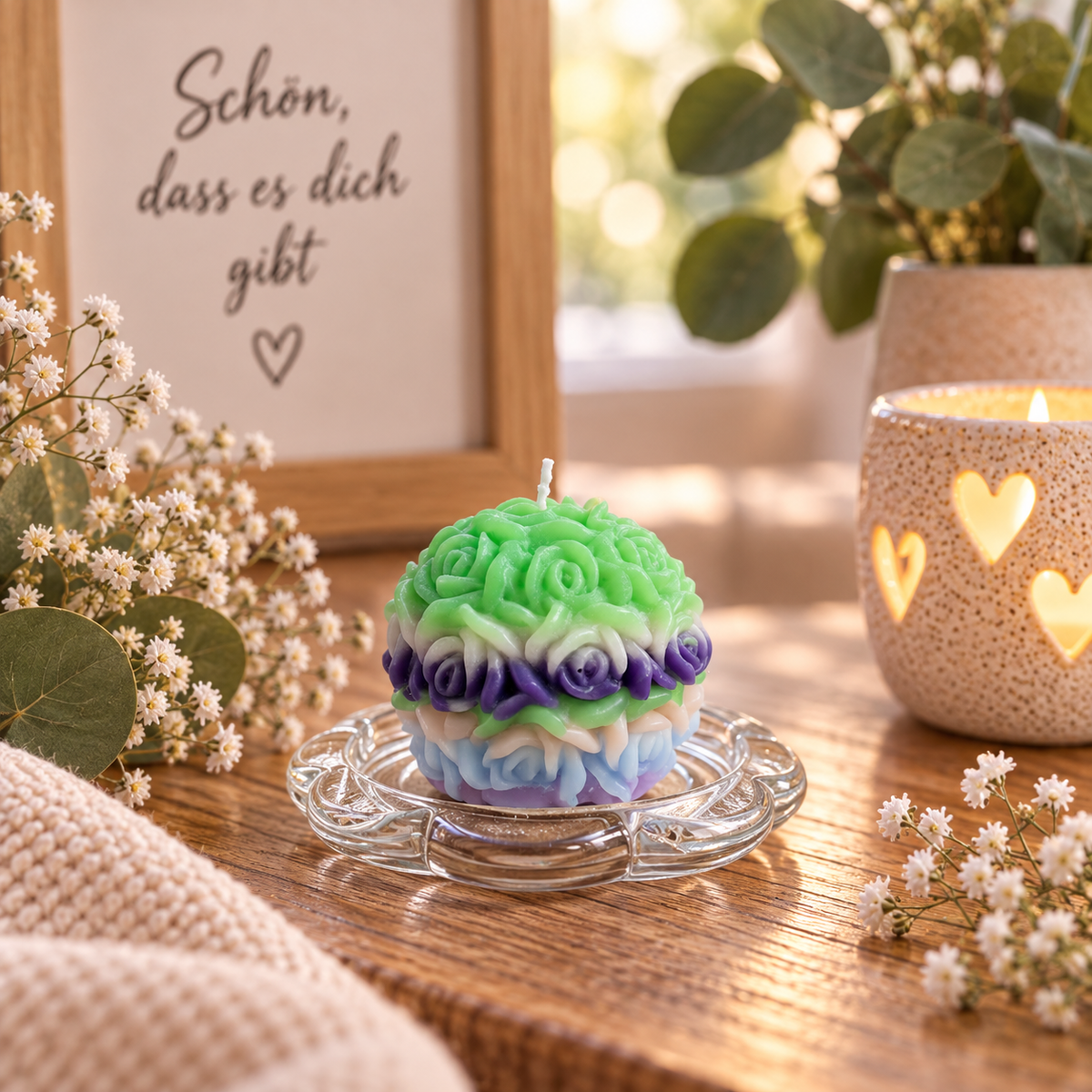 Handgegossene mehrfarbige Rosenkerze in Grün, Lila und Hellblau in gemütlichem Wohnambiente