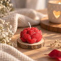  Handgemachte rote Lotuskerze auf Holzscheibe in gemütlicher Dekoration mit weißen Blumen.