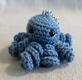 Blauer gehäkelter Tintenfisch als Schlüsselanhänger im Amigurumi Stil, handgemacht mit liebevollen Details
