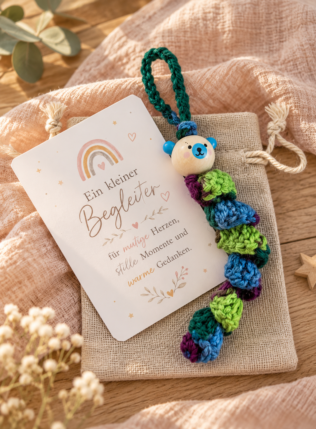 Handgemachtes Sorgenbärchen als bunte Häkelraupe mit Stoff-Säckchen und Karte „Ein kleiner Begleiter“