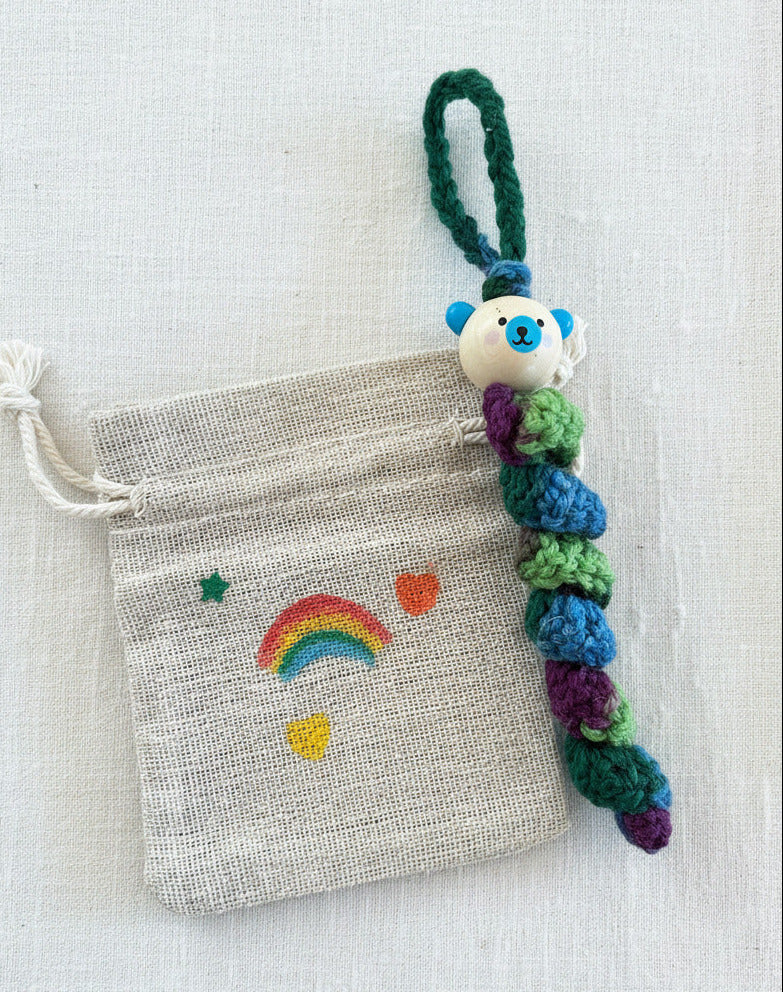 Handgemachtes Sorgenbärchen in Regenbogenfarben neben kleinem Stoffbeutel mit Regenbogenmotiv 🌈🧸