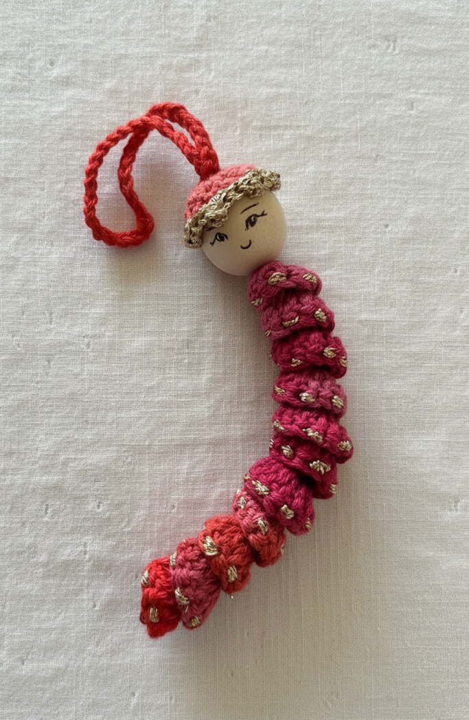 Gehäkeltes Sorgenwürmchen in Rosa mit Gesicht und Aufhängeschlaufe, handgemachter Glücksbringer