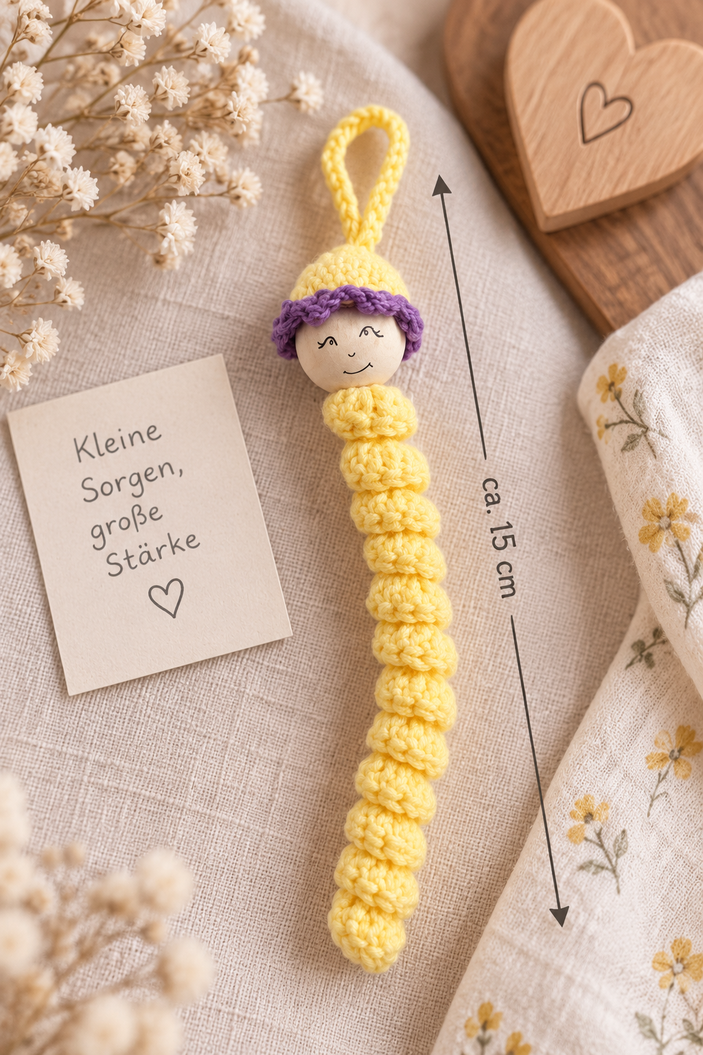 Handgemachtes gelbes Sorgenwürmchen mit lila Mütze, ca. 15 cm groß, liebevoll als kleiner Glücksbringer gestaltet.