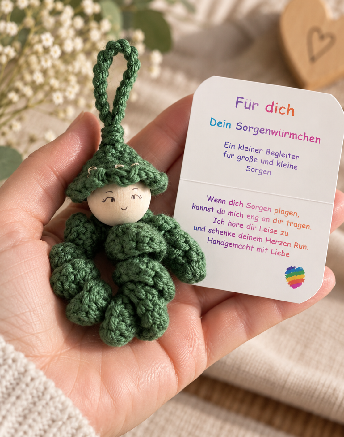 Handgemachtes grünes Sorgenwürmchen mit Kärtchen „Für dich“ liebevoll in einer Hand gehalten