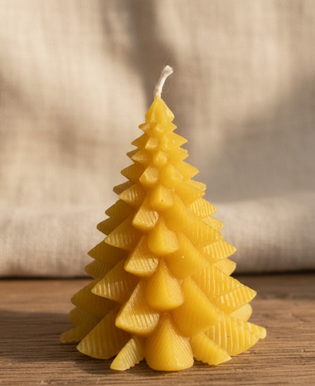 Handgegossene Tannenbaum-Kerze in Gelb – dekorative Weihnachtsbaum-Kerze auf Holztisch
