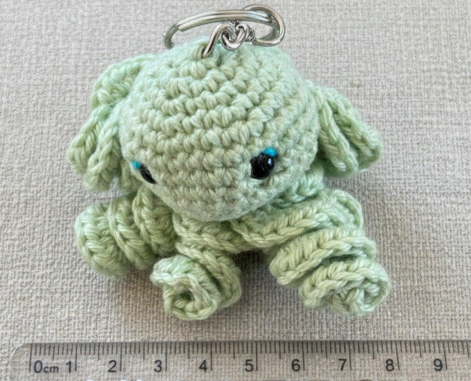 Grüner gehäkelter Tintenfisch als Schlüsselanhänger im Amigurumi Stil mit Lineal zum Größenvergleich, handgemacht