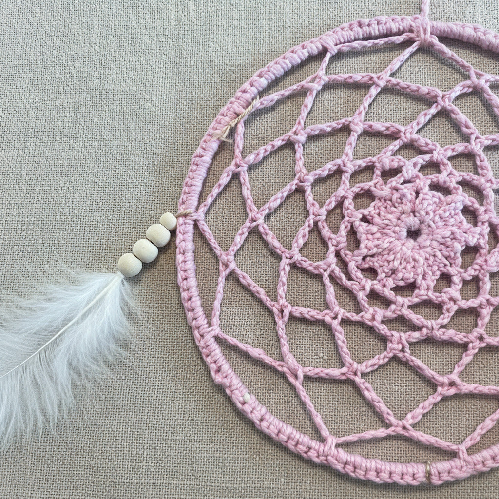 Detailaufnahme eines handgemachten rosa Traumfängers mit gehäkeltem Netz und Holzperlen im Boho Stil