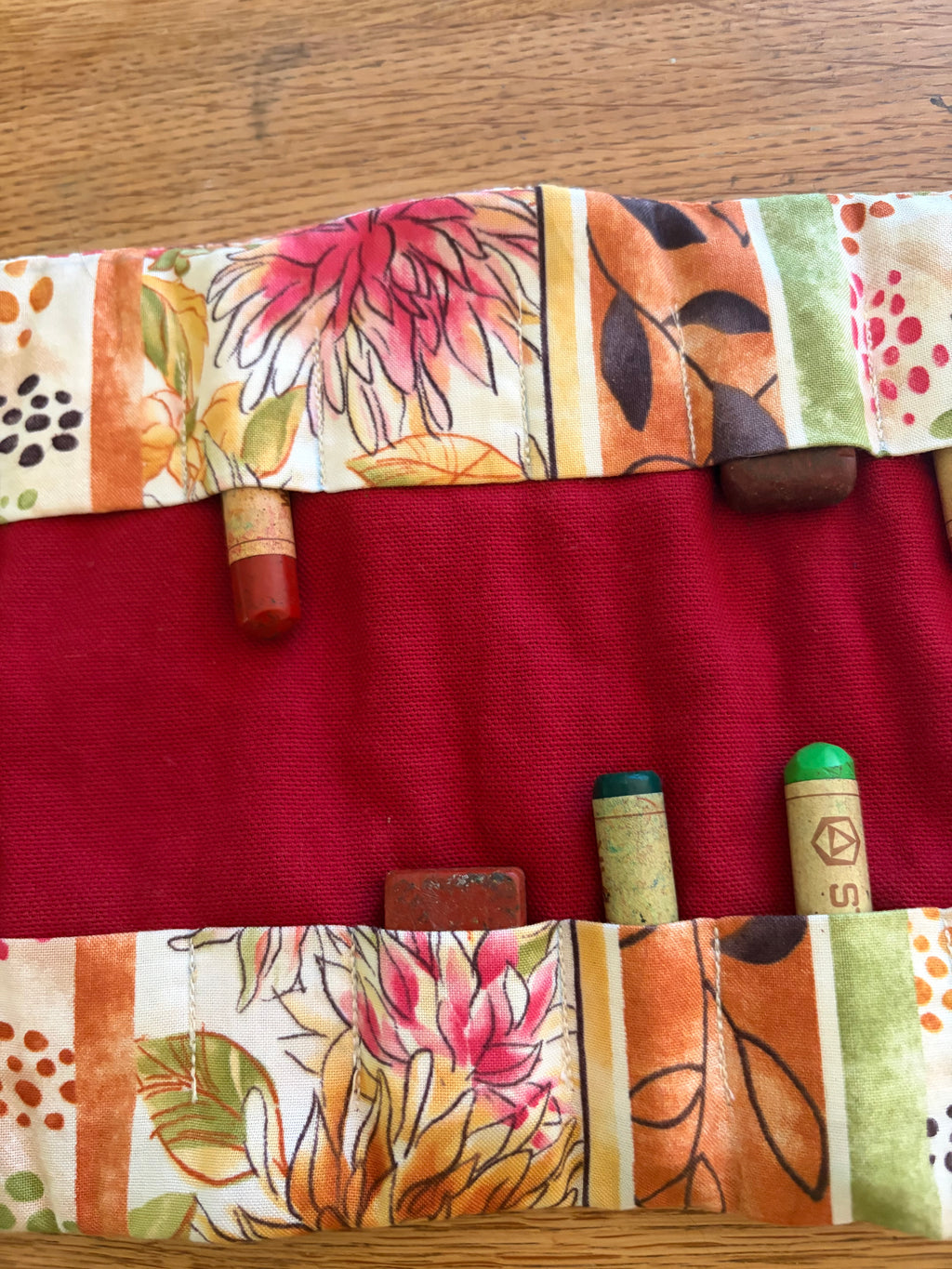Detailansicht eines handgefertigten Waldorf Rollmäppchens mit Blumenstoff und Fächern für Wachsmalblöcke und Wachsmalstifte.