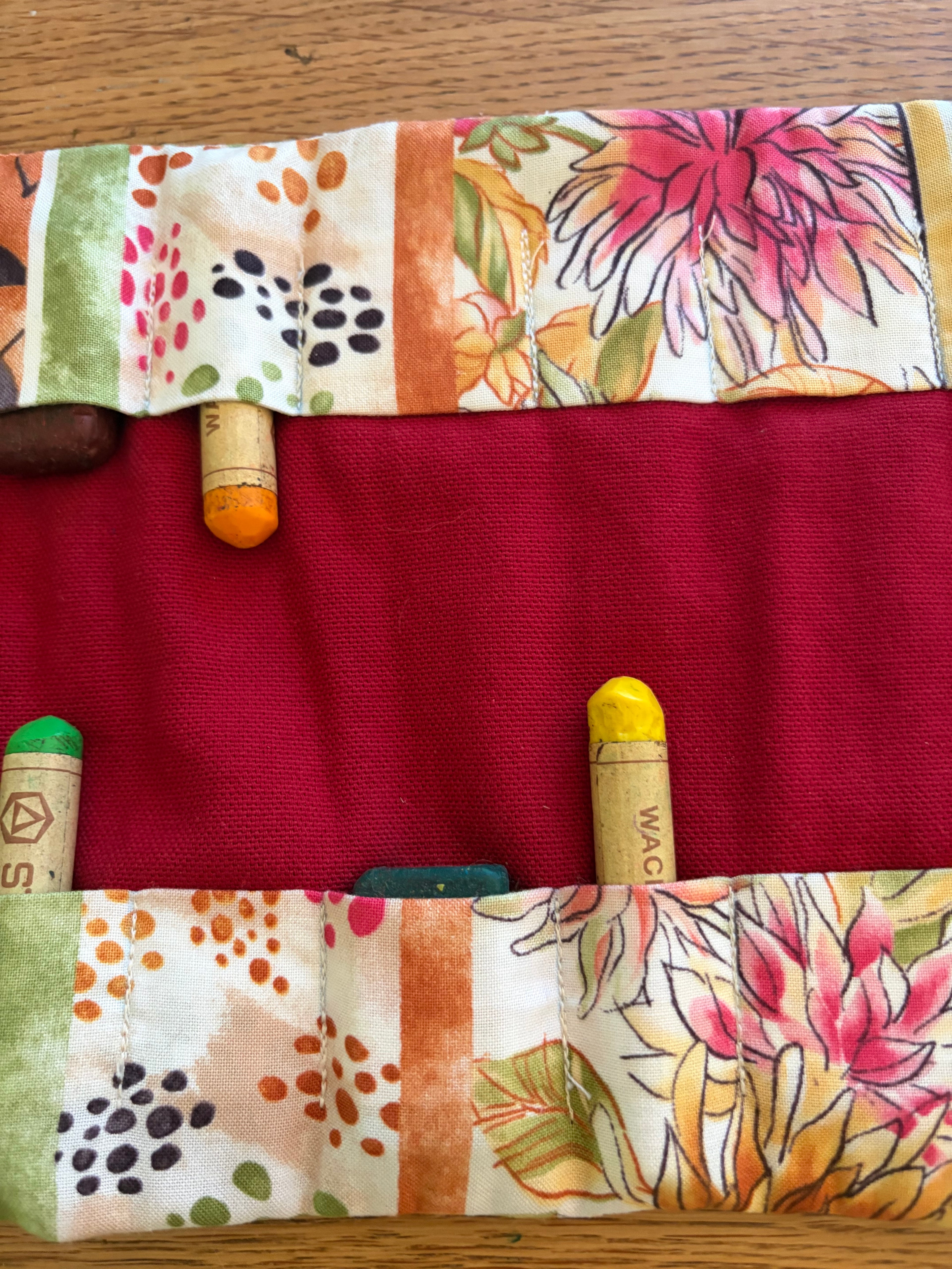 Detailansicht eines Waldorf Rollmäppchens mit Blumenmuster und Fächern für Wachsmalstifte und Wachsmalblöcke.