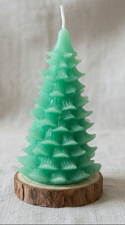 Handgemachte grüne Weihnachtsbaum Kerze aus Kerzenresten auf Holzunterlage